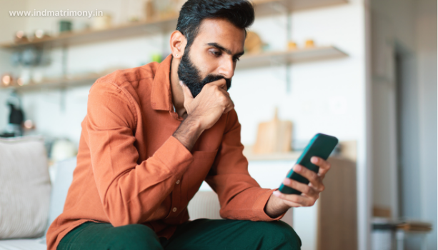 Man thoughtfully checking phone on matrimony app, reflecting the question is matrimony and marriage the same.